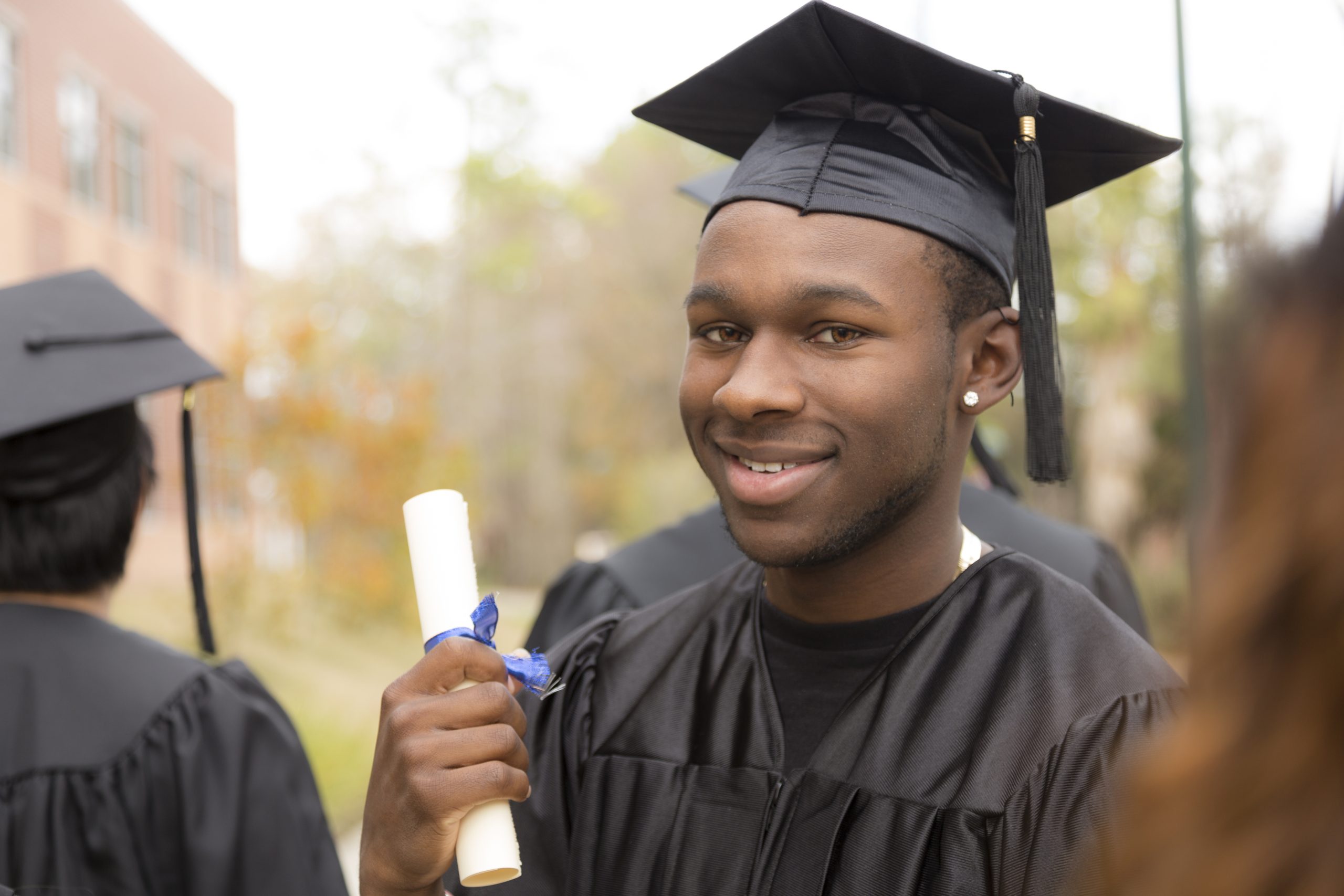 Male graduate excitedly holding his diploma after the high school or college graduation ceremony. 