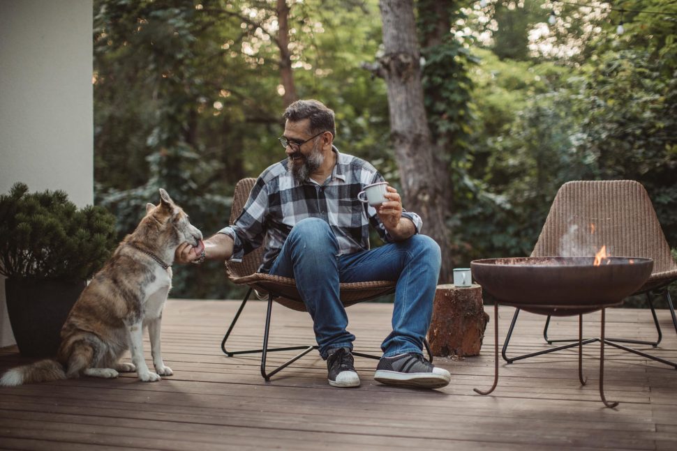 male teacher drinking coffee with a dog on a porch