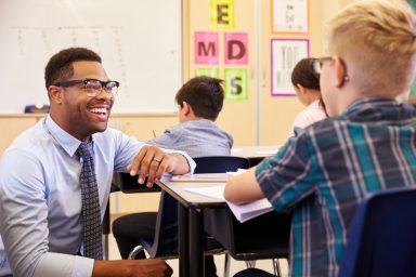 African American Male teacher assisting a student in class